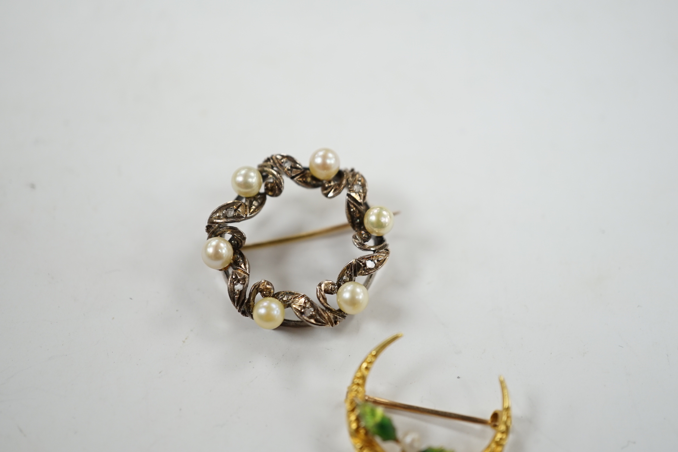 A yellow metal enamel and small baroque pearl set folate crescent brooch, 27mm, together with a yellow metal, cultured pearl and diamond chip set openwork circular brooch.